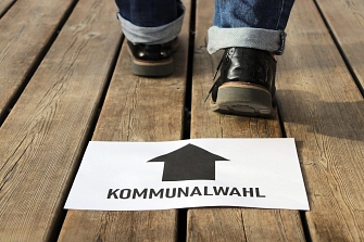 Kommunalwahl.jpg Zwei Füße, die in Richtung eines Schildes mit Pfeil und Aufschrift "Kommunalwahl" gehen.
